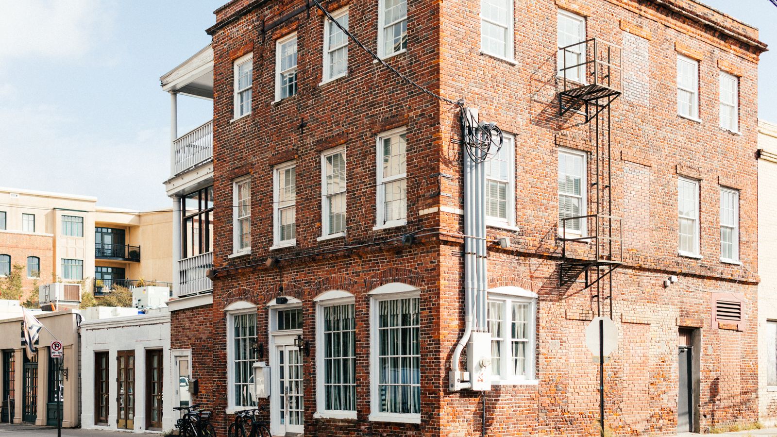 Corner of a small brick apartment building with bikes parked outside, the kind of fourplex where a landlord might offer a lease for Airbnb arbitrage